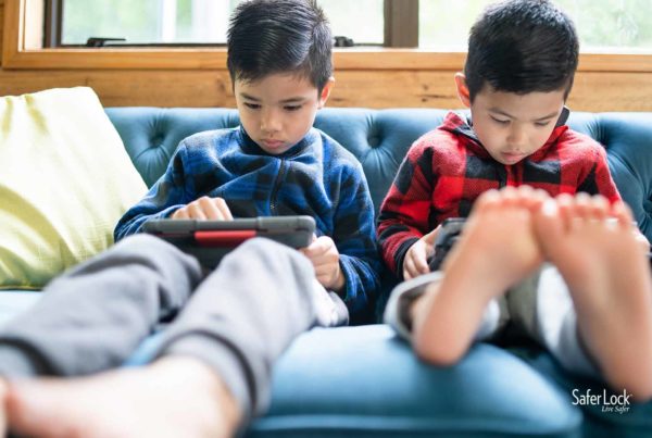 Two young boys sitting on a couch using tablets. Discover how to keep kids safe online.