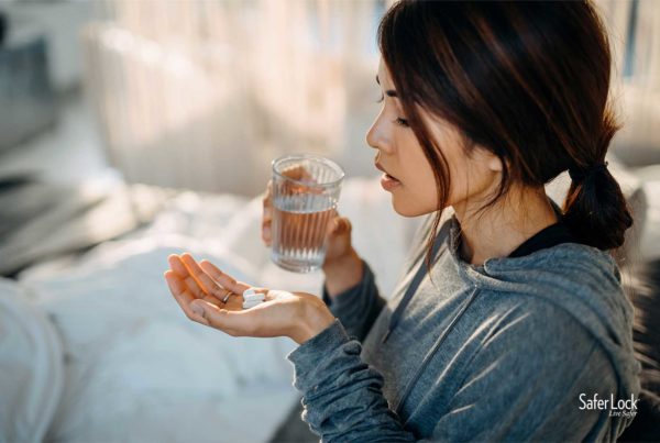 A young Latina woman with a glass of water and prescription pills. Learn how to use opioids safely at SaferLockrx.com